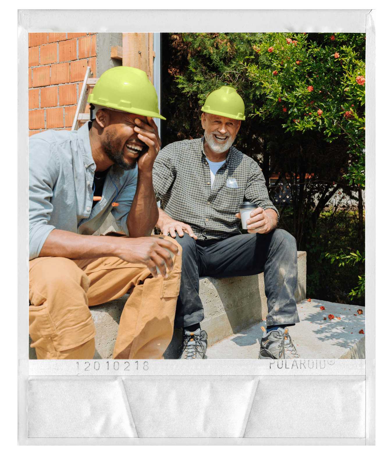 Polaroid-style photo of two construction workers in hard hats laughing on a job site